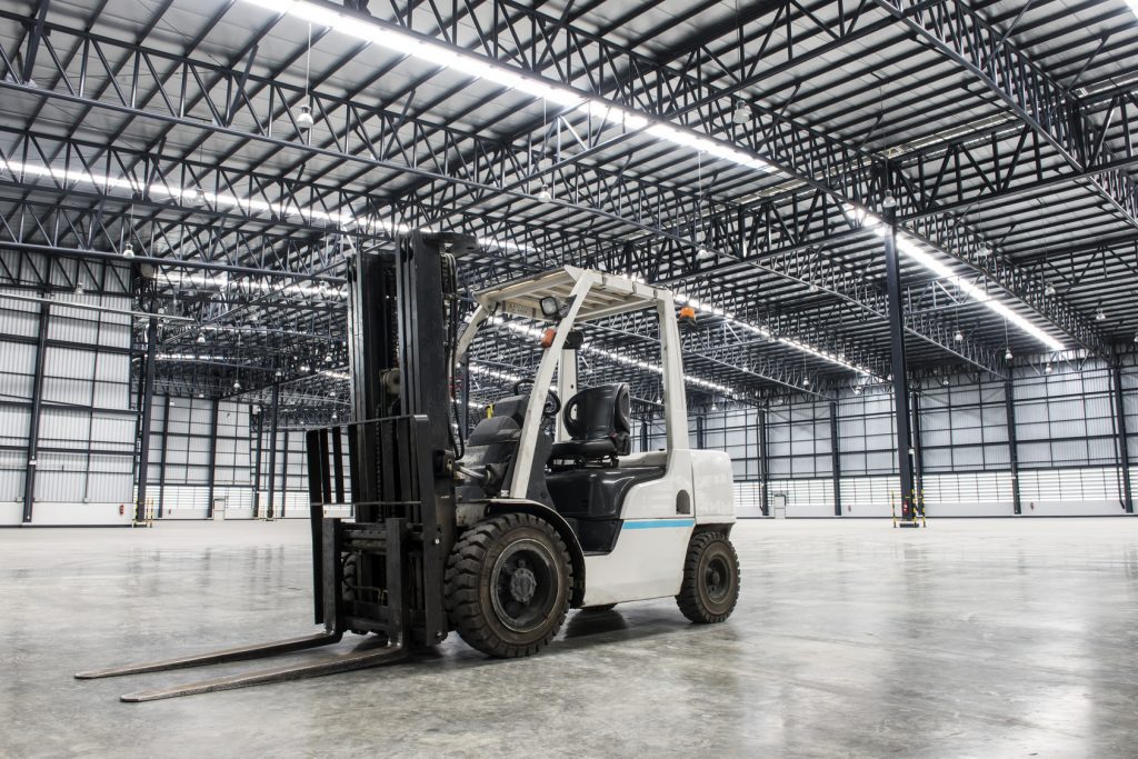 A white forklift inside an empty warehouse